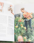 photo of a page inside the book of a woman in a garden holding orange dahlias
