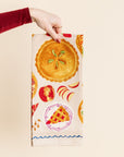 Hand holding a decorative towel with pie design on a beige background