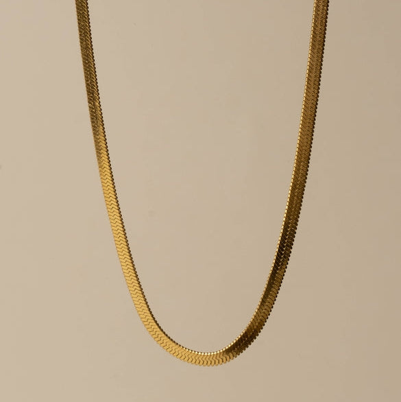 Gold chain necklace on a beige background