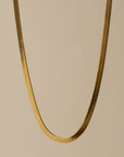 Gold chain necklace on a beige background