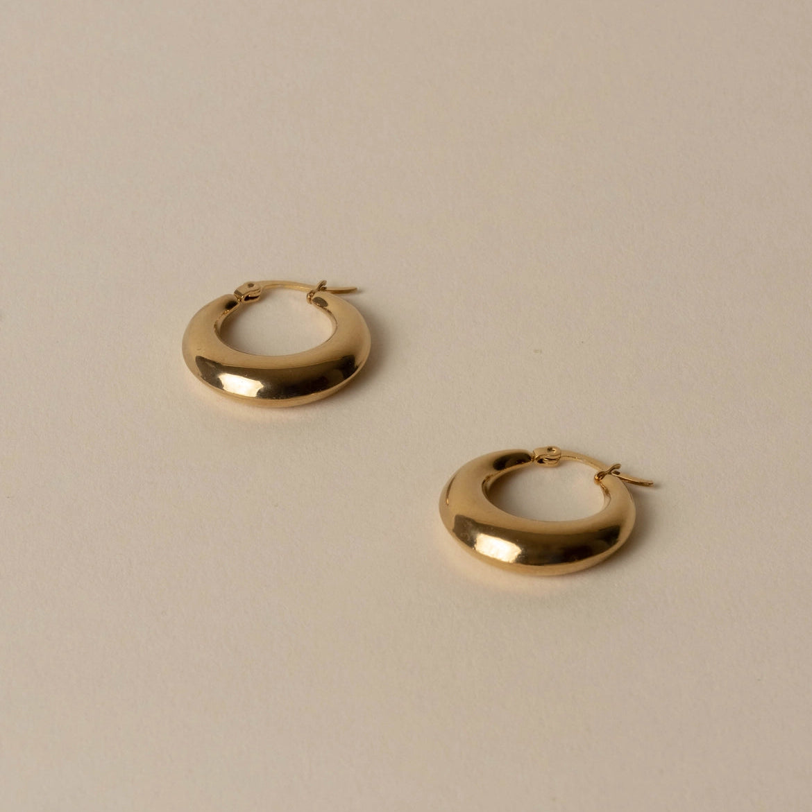 Gold hoop earrings on a beige background