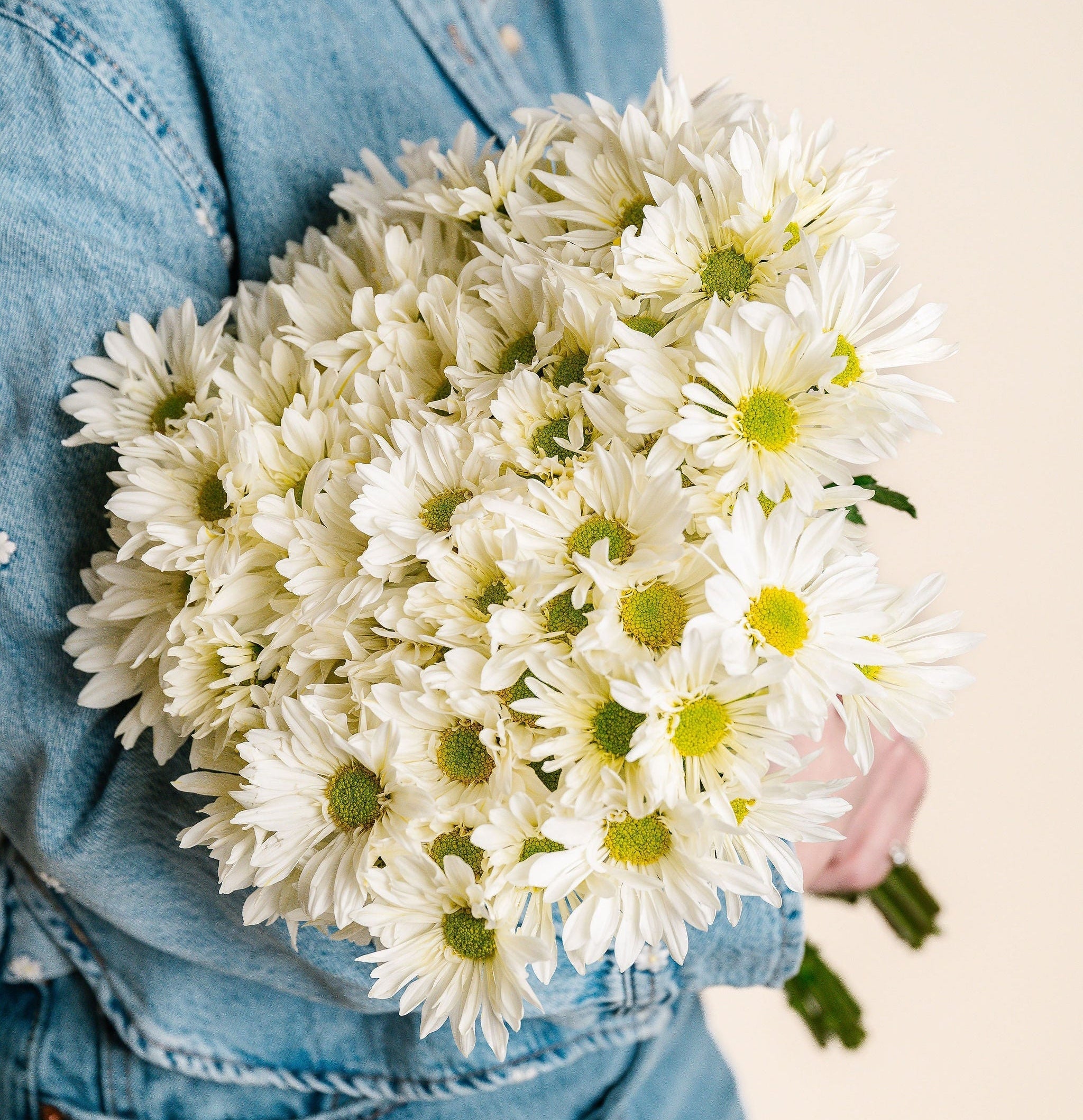 Person holding a bouquet of white flowers against a neutral background
