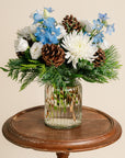 Glass vase with flowers and pinecones on a wooden table