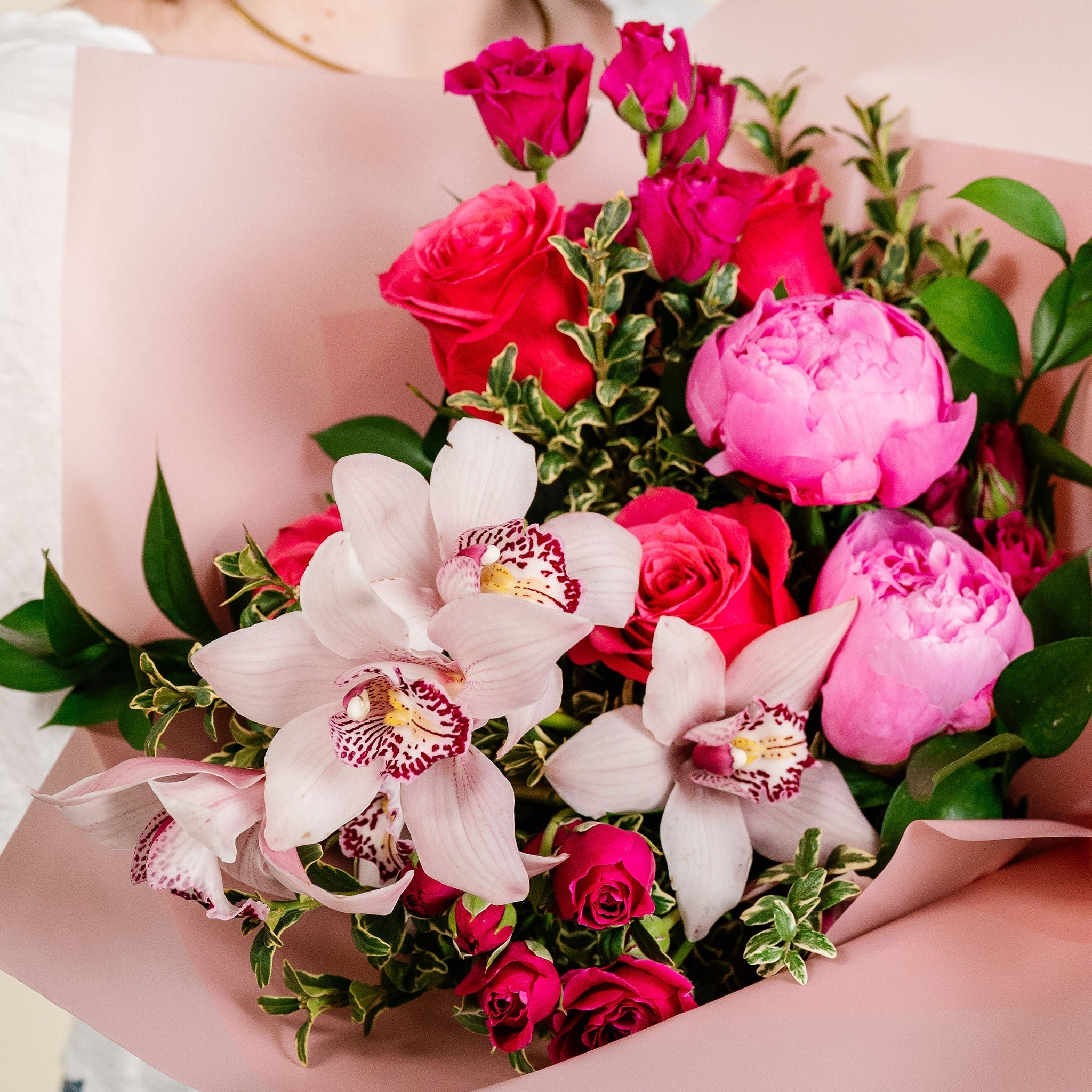 Person holding a bouquet of pink and red flowers